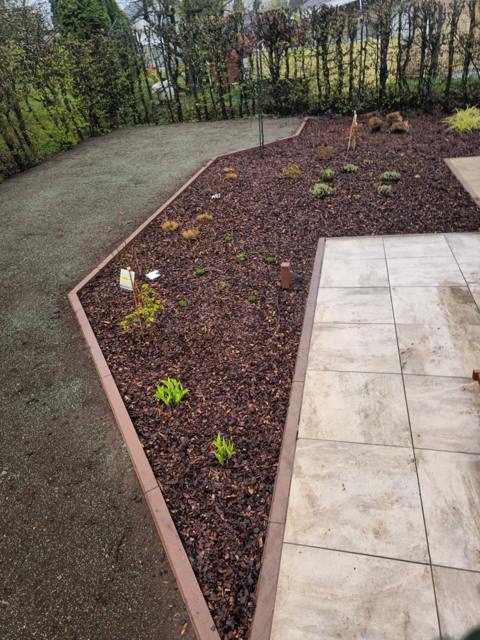 Beet mit Rindenmulch entlang eines Plattenwegs