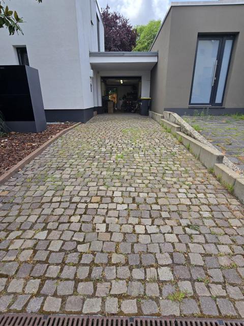 Einfahrt mit Natursteinpflaster vor modernem Wohnhaus
